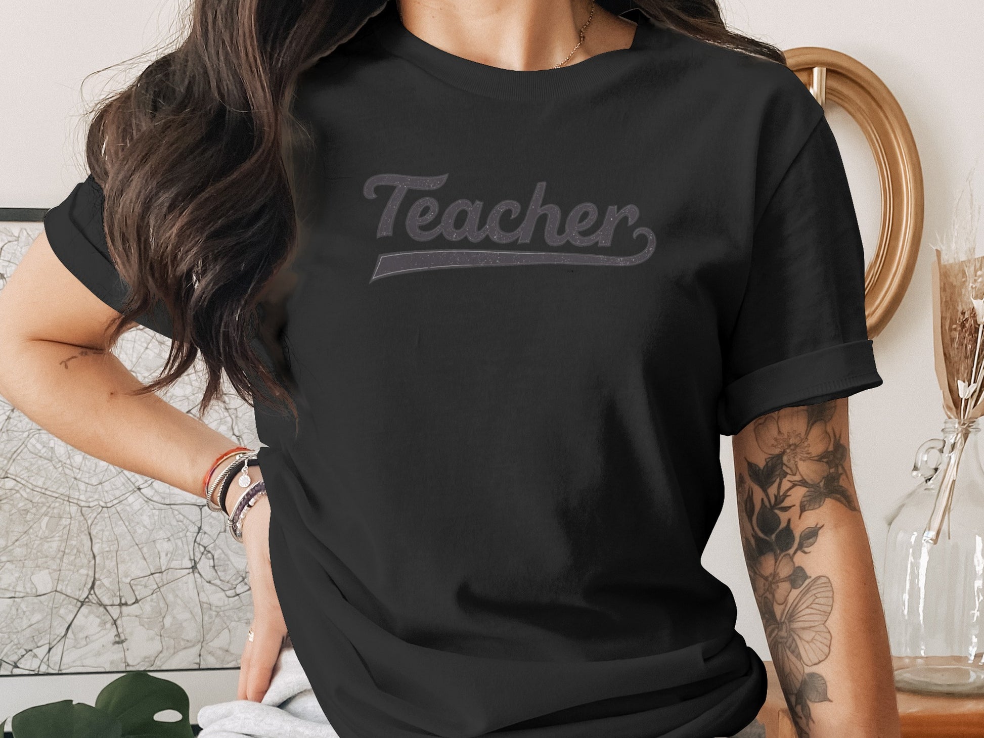 Black t-shirt with "Teacher" printed in grey on chest.