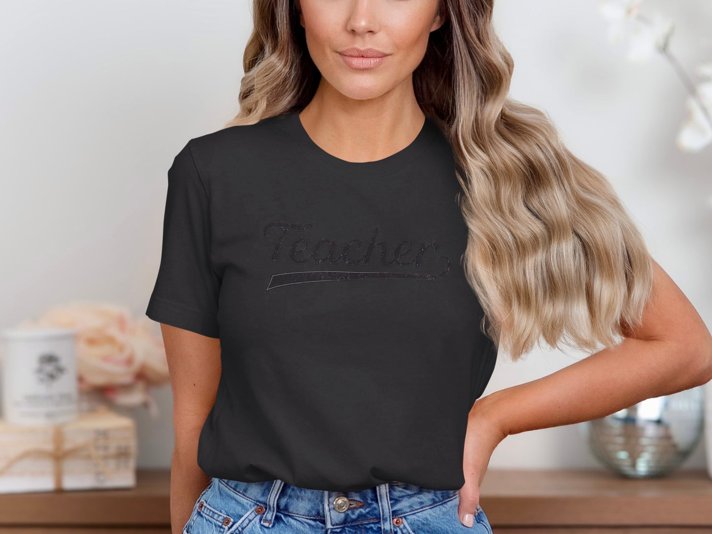 Black t-shirt with "Teacher" text in glitter on a woman.