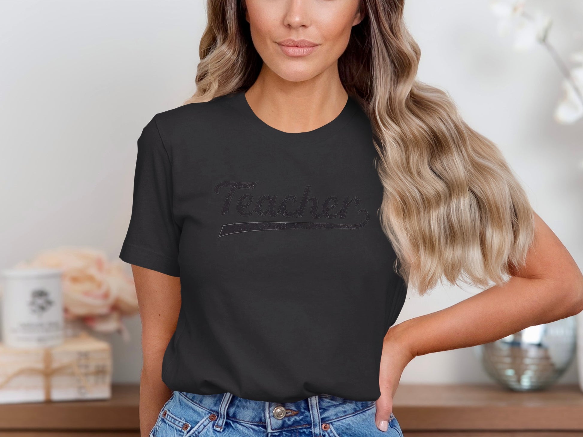 Black t-shirt with "Teacher" text in glitter on a woman.